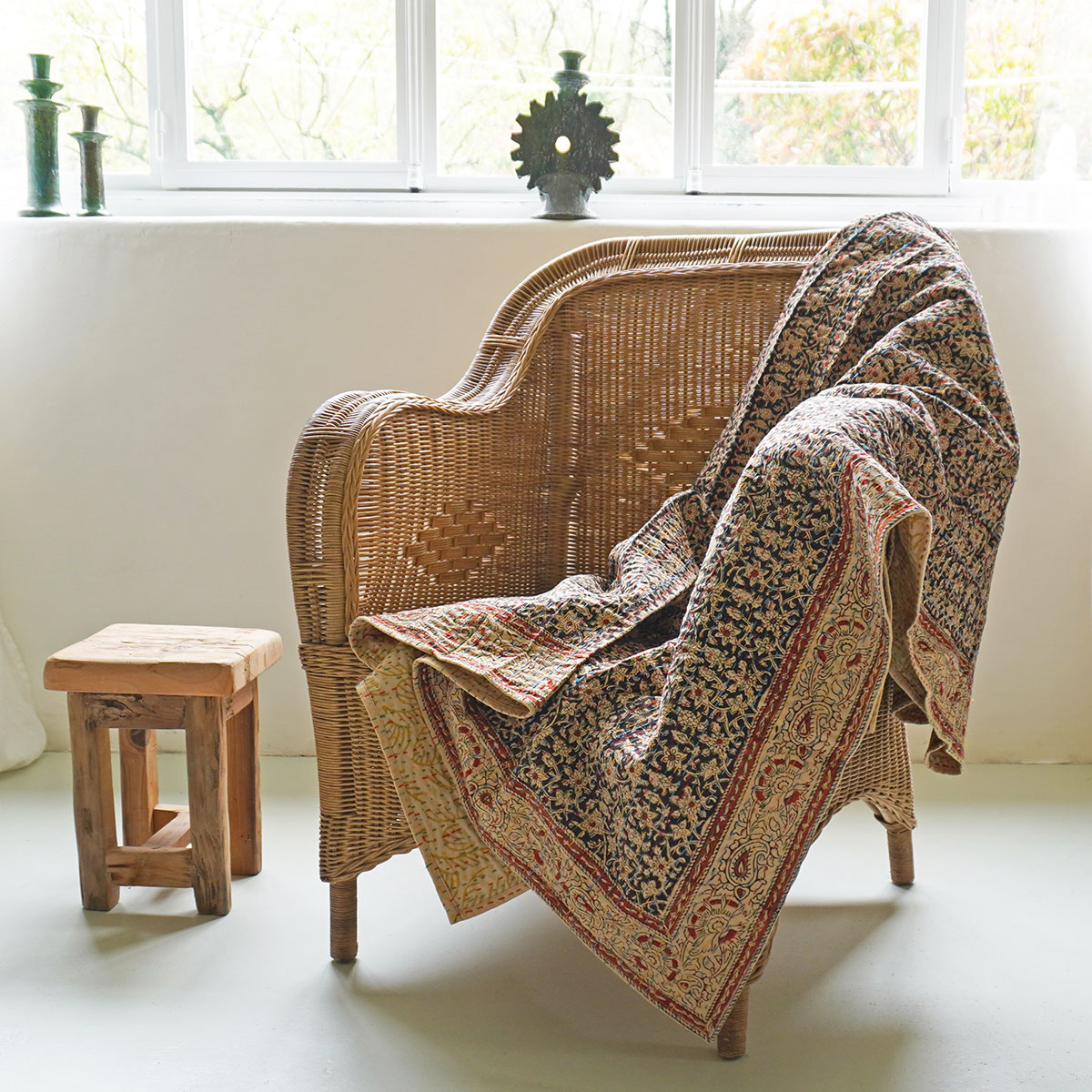 Fauteuil en rotin tressé et plaid kantha