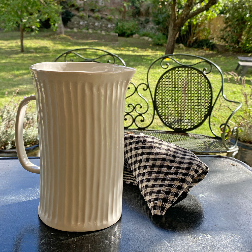 Pichet ou Carafe ou cruche en céramique blanche striée avec anse, facile à harmoniser. Chaque pichet est peint à la main, collection Yolanda signée marque suédoise Olsson & Jensen, présentée ici avec la torchon en lin vichy Vipa