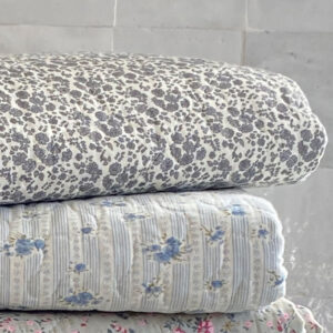 Courtepointe ou plaid en coton matelassé cocooning surpiqué finition quilt. Motif Betty fleurs bleues ou gris ardoise sur fond blanc style scandinave et hivers cosy de l'esprit Hygge cocooning