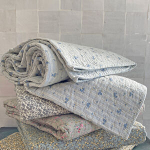 Motif Rosalie Courtepointe ou plaid en coton matelassé cocooning surpiqué finition quilt. Fleurs et rayures bleues sur fond blanc style scandinave et hivers cosy de l'esprit Hygge cocooning